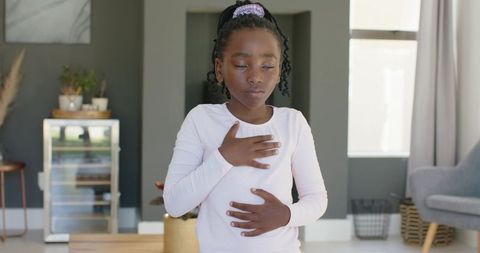 African girl practicing deep breathing meditation at home for calm, focus and mindfulness
