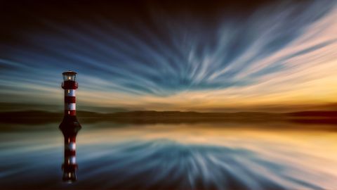 Dramatic seascape view with lighthouse at sunset