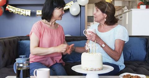 Senior Friends Sharing Coffee at Birthday Celebration in Cozy Living Room