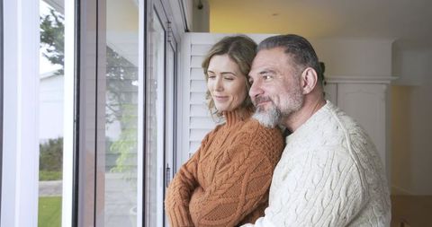 Couple Embracing While Looking Out Bright Window