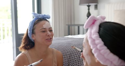 Joyful Friends Applying Face Masks Relaxing at Home