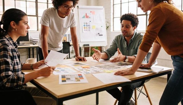 Creative team collaborating over design mockups and color palettes, planning product layouts