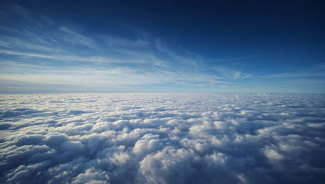 Vast Cumulus Cloud Sea Rolling Beneath Deep Blue Sky with Delicate Cirrus Streaks