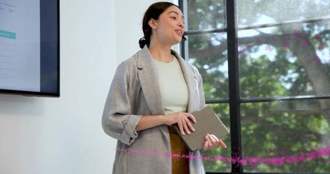 Presenting confident mid-adult woman holding tablet and speaking with headset microphone