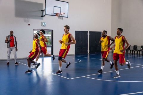 Diverse Basketball Team Training in Gym with Coach