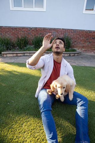 Man sitting outdoors with golden retriever puppy, leisure and companionship
