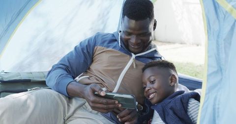 Father and Son Bonding Under Tent with Smartphone