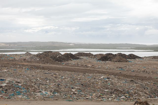 General view of rubbish piled on a landfill full of trash with cloudy overcast sky in the background. Global environmental issue of waste disposal.