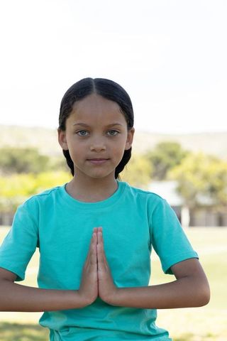 Preteen girl practicing mindfulness outdoors holding palms pressed in namaste pose