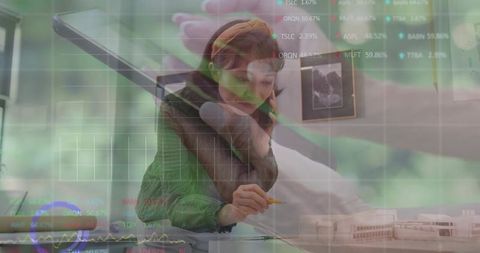 Architectural designer sketching plans while talking on phone with digital charts and model