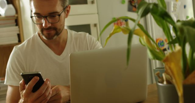 Young Man Working from Home Using Smartphone and Laptop - Download Free Stock Images Pikwizard.com