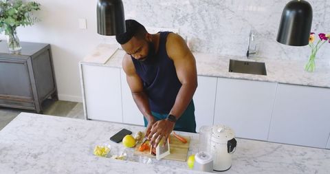 Man grating carrots in modern home kitchen for healthy meal prep