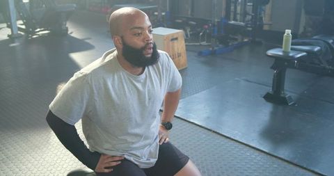 African american man kneeling and preparing for lift on rubber gym floor during strength training