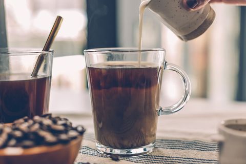 Close-up of coffee pouring with beans and glass cup