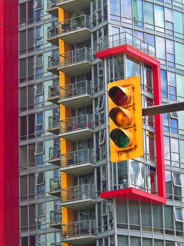 Traffic light glowing against colorful modern high-rise with balconies and glass facades