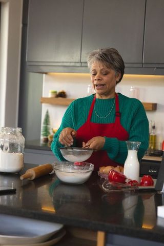 Senior woman sifting flour in modern kitchen interior