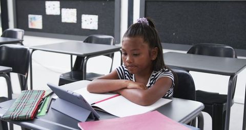 Focused african american girl learning with tablet in classroom
