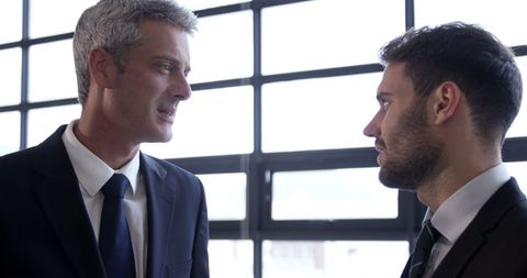 Two Businessmen Engaged in Serious Discussion Near Office Window - Download Free Stock Images Pikwizard.com
