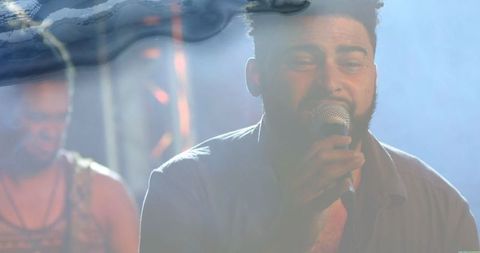 Bearded singer encircled by moody concert stage haze