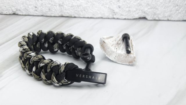 Tactical paracord bracelet with a flint firestarter displayed on a marble surface, emphasizing survival and emergency readiness gear. Ideal for outdoor enthusiasts, campers, and hikers. Can be used in promotional materials for survival equipment, adventure gear catalogs, and emergency preparedness product listings.