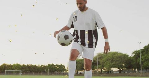 Soccer Player Juggling Ball on Field with Striped Jersey