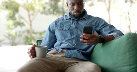 Relaxed Man Enjoying Coffee and Smartphone at Home