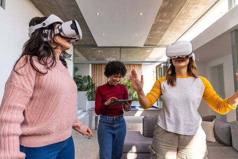 Diverse friends exploring virtual reality with headsets in sunlit modern living room