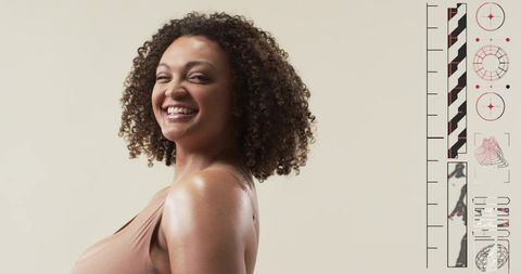 Confident smiling woman with curly hair posing three-quarter on minimalist beige backdrop