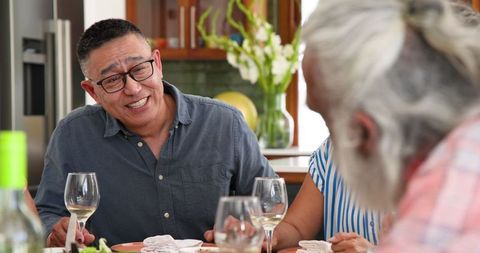 Senior Friends Enjoying Dinner Conversation Over Wine