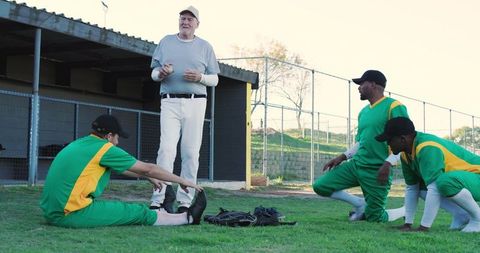 Veteran coach leading baseball team during sunny outdoor practice and warm-up drills