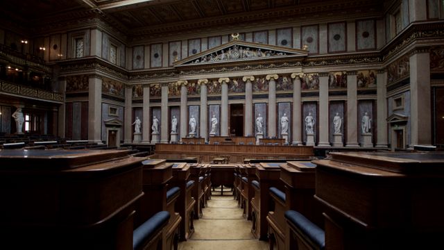 This image captures an empty, grand courtroom with classic architecture featuring ornate columns and statues. Perfect for use in articles or projects related to law, justice, and historic or governmental buildings. Ideal for illustrating legal concepts, history, and architecture.