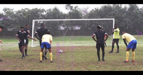 Youth soccer players forming defensive wall preparing free kick on overcast park field