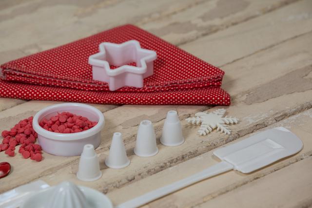 Christmas baking tools and decorations are arranged on a wooden surface. Items include a star-shaped cookie cutter, a spatula, dessert toppings, and a snowflake decoration. This image is perfect for holiday-themed cooking blogs, festive recipe websites, and Christmas baking promotions.