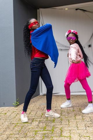 African american girls posing as superheroes wearing blue cape and pink tutu outdoors