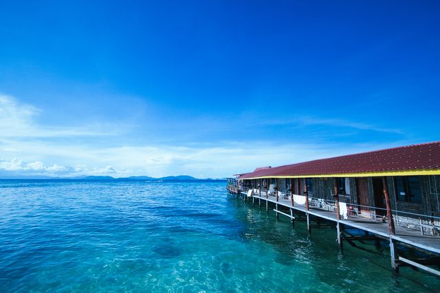 This scene showcases a peaceful overwater bungalow resort on a clear day. The calm blue water and serene atmosphere make it perfect for vacation brochures, travel blogs, tourism websites, and promotional materials for luxury or tropical locations. The picturesque view emphasizes relaxation, making it an attractive option for marketing vacation packages.
