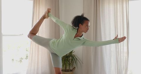 Woman Practicing Yoga at Home in Green Activewear