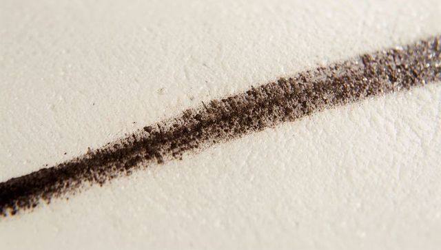 Macro close-up diagonal graphite stroke on rough textured drawing paper with pigment dust