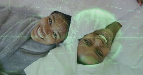 Smiling mother and daughter relaxing in towels on bed with digital wellness overlay