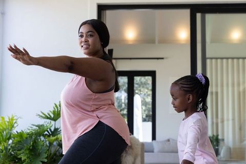 African american mother and daughter doing at-home stretching and workout together smiling