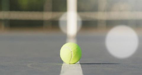 Yellow Tennis Ball Resting on Center Line of Outdoor Court