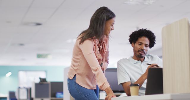 Two colleagues discussing work in a modern open office setting - Download Free Stock Images Pikwizard.com