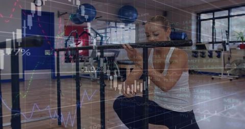 Kneeling woman adjusting ballet barre in fitness studio with stock market charts overlay