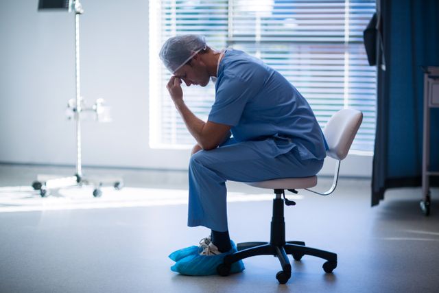 Tensed male nurse sitting in corridor of hospital
