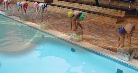 Young swimmers preparing to dive at pool's edge
