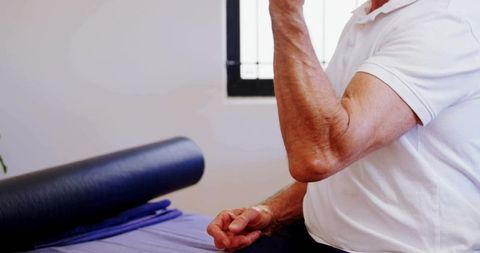Senior man performing forearm exercise with foam roller during rehabilitation session