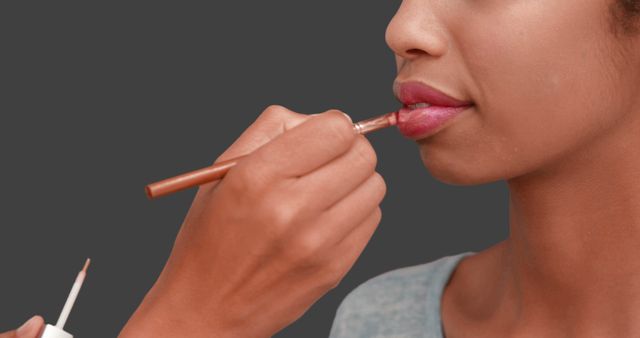 Make up artist putting lip gloss on models face on grey screen background - Download Free Stock Photos Pikwizard.com