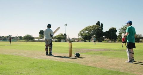 Bowling to batsman missing shot with wicketkeeper collecting ball on sunny cricket pitch