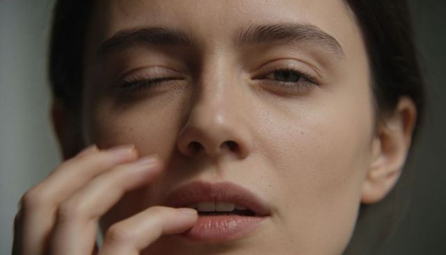 Woman touching lower lip closeup showing natural skin texture and intimate expression