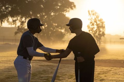 Sunrise baseball teammates shaking hands and holding bats showing sportsmanship