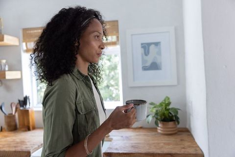 African american woman holding coffee mug in rustic kitchen cozy minimalist morning moment